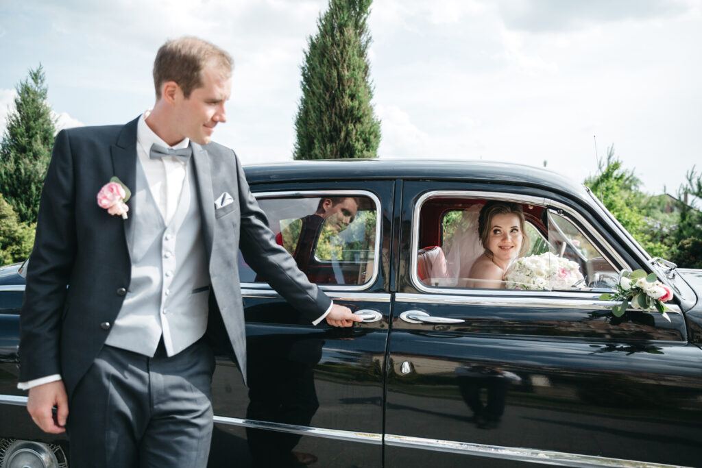 Newlyweds entering a luxury vehicle with driver assistance, highlighting seamless wedding transfer service.